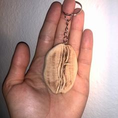 a hand holding a wooden keychain with a woman's face on it