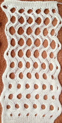 a white crochet doily with holes on it sitting on a brown surface