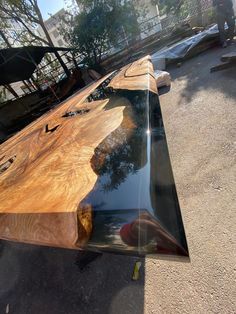 a large wooden table sitting on top of a parking lot next to a forest filled with trees