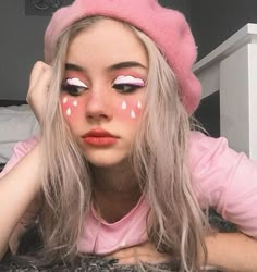 a girl with pink and white makeup looks at the camera