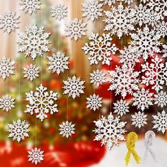 snowflakes are hanging from strings in front of a christmas tree with a yellow ribbon