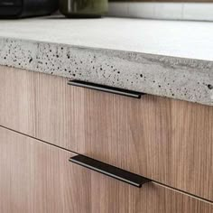 a kitchen counter top with two black handles on the bottom and an oven in the background