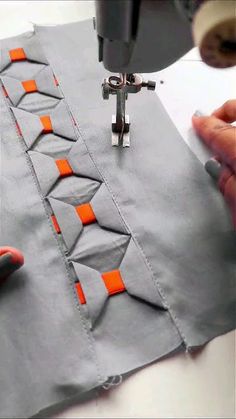 someone is using a sewing machine to sew on some fabric with an orange strip