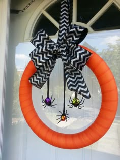 an orange wreath with black and white spider decorations hanging from it's front door