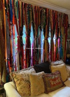 a living room filled with lots of different colored ties hanging on the wall behind a white couch