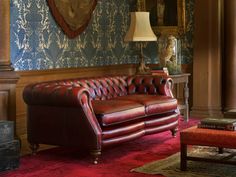 a red leather couch sitting in front of a fireplace