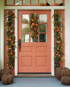 an orange front door decorated with pumpkins and greenery