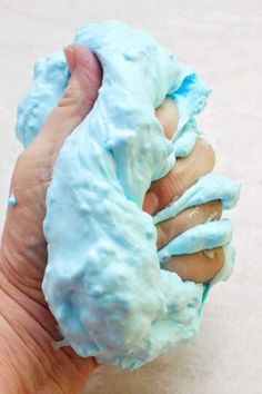 a hand holding something blue and white in it's left hand, with the other hand reaching out