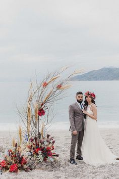 a man and woman standing next to each other on a beach