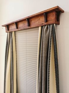 a window with some curtains hanging on it's side and a wooden shelf above the blinds