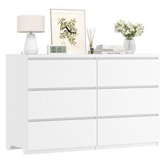 a white dresser with flowers and pictures on top