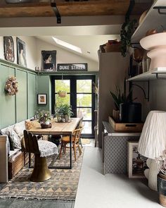 an open kitchen and dining room with lots of plants on the shelves above the table