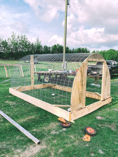 a chicken coop in the middle of a field with wheels on the ground and grass around it