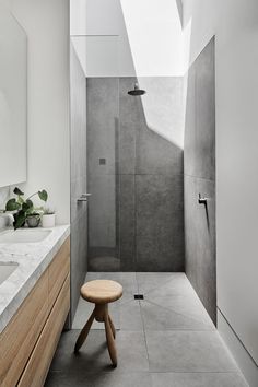 a modern bathroom with a skylight above the shower and stool in front of it