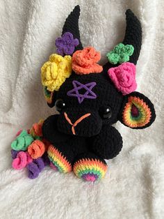 a black stuffed animal with multicolored crocheted flowers on it's head