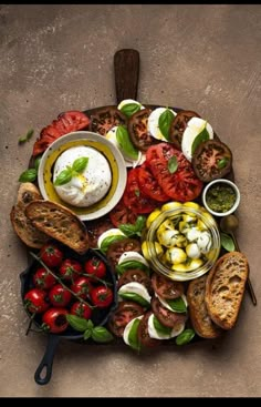 a platter filled with bread, tomatoes and other food on top of a table