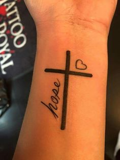 a woman's wrist with a cross on it and the word hope written in cursive font