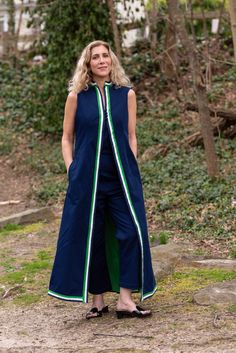 a woman standing in the woods wearing a blue and green dress with an open front