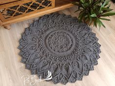 a gray rug sitting on top of a wooden floor next to a potted plant