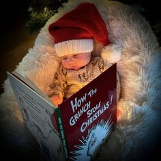 a baby wearing a santa hat is reading a book