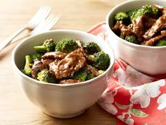 two white bowls filled with meat and broccoli on top of a wooden table