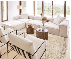 a living room filled with white furniture and large windows overlooking the mountains in the distance