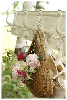 a basket with flowers hanging from the side of a bench next to a flower pot