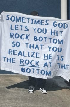 a person holding up a sign that says sometimes god lets you hit rock bottom so that you realize he is the rock at the bottom