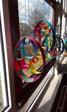 colorful paper circles are hanging on the window sill