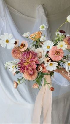 a bouquet of flowers is sitting on a white cloth draped over the back of a chair