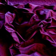 an image of a bed that is covered in purple sheets and blankets on top of each other