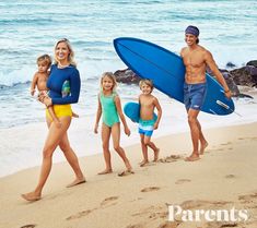 the family is walking on the beach with their surfboards