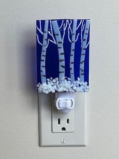 a light switch cover with blue and white trees painted on the wall next to it