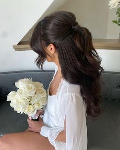 a woman sitting on top of a couch holding a bouquet of flowers in her hand