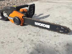 an orange and black chainsaw sitting on the ground