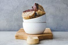 two pieces of cake in a white bowl on a wooden board next to a gray wall