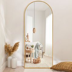 a mirror sitting on top of a wooden floor next to a white chair and table