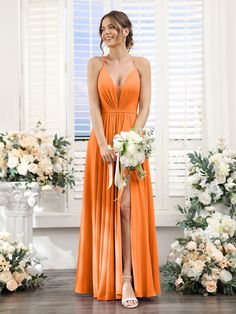 a woman in an orange dress standing next to flowers