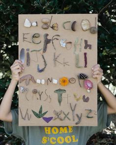 a person holding up a cardboard sign with letters and numbers made out of various objects