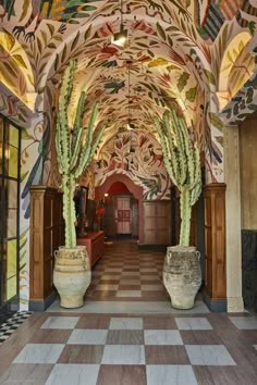 the hallway is decorated with intricately designed murals and large potted cacti