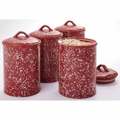 three red canisters with lids and handles, one has white speckles on it