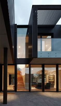 the inside of a modern house with glass walls and stairs leading up to the second floor