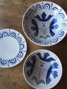 three blue and white bowls sitting on top of a wooden table