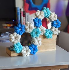 a crocheted wreath sitting on top of a wooden stand next to a computer monitor