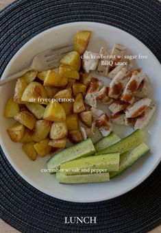 a white plate topped with chicken, potatoes and cucumbers next to a fork