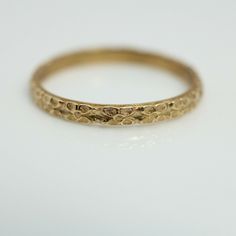 a gold wedding band on a white surface