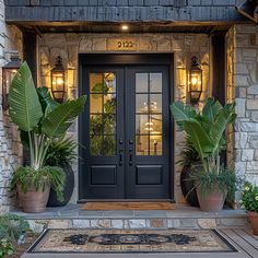 two large plants are in front of the entrance to a house with stone walls and doors