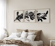 two black and white paintings on the wall above a bed in a room with beige linens