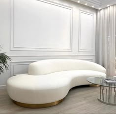 a living room with white furniture and a glass table on the floor in front of it