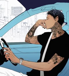 a man with tattoos sitting in a car holding a steering wheel and looking at his cell phone